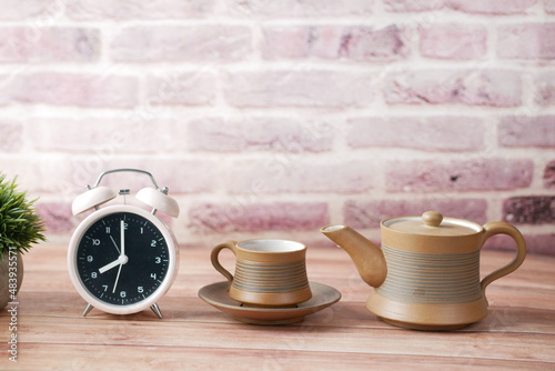 tea cup and table clock on table 