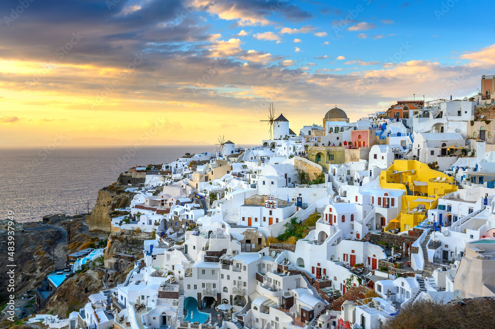 Panorama of the city of Oia on the island of Santorini, Greece. Picturesque houses and churches with blue domes at sunset, Aegean Sea