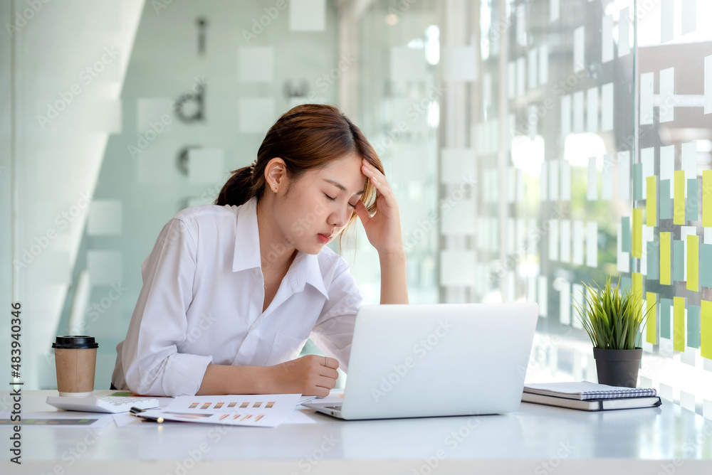 Young Asian businesswoman sitting in the office feeling stressed or tired from work. Young Asian businesswoman sitting in the office feeling stressed or tired from work.