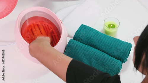 Woman in beauty salon getting parrafin bath procedure to make her hands soft and beautiful, health skin concept. photo