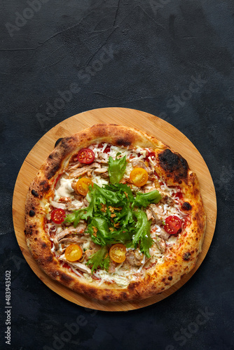 Pizza Caesar. Pizza with chicken, tomato, cheese and lettuce on stone background. Top view. Free space for your text. Delivery food
