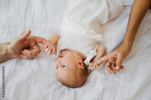 Mom and dad are holding the hands of a newborn girl. Close-up photo.