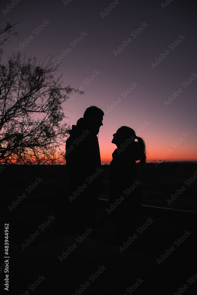 Silhouette of a man and a woman enjoying sunrise on the beach
