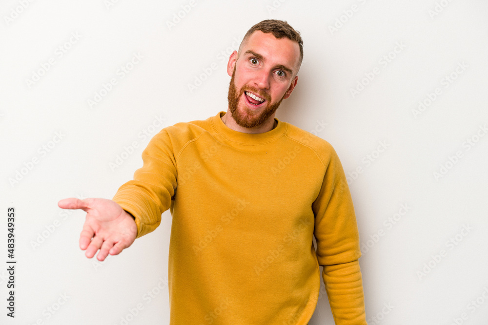 Obraz premium Young caucasian man isolated on white background stretching hand at camera in greeting gesture.