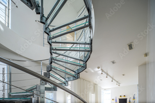 Modern interiro of luxury private house. Glass metal spiral staircase.