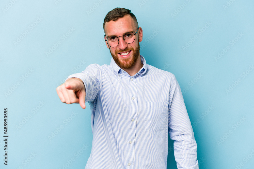 Fototapeta premium Young caucasian man isolated on blue background cheerful smiles pointing to front.