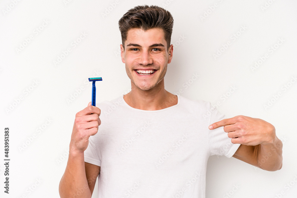 Young caucasian man shaving his beard isolated on white background person pointing by hand to a shirt copy space, proud and confident Young caucasian man shaving his beard isolated on white background person pointing by hand to a shirt copy space, proud and confident