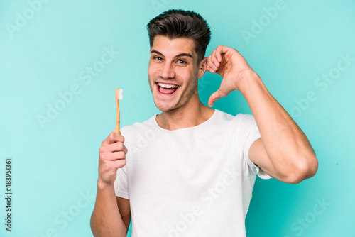 Young caucasian man brushing teeth isolated on white background feels proud and self confident, example to follow.