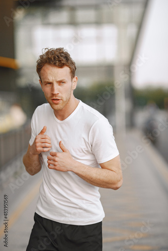 Portrait of a young fit man jogging outdoors on a stadium