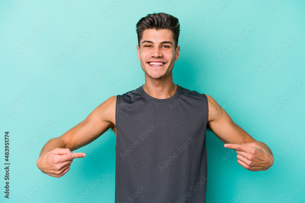 Fototapeta premium Young caucasian man isolated on blue background points down with fingers, positive feeling.