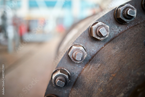 Foto Industry flanges joint connection with screws and bolts closeup over out of focus abstract industrial background with copyspace