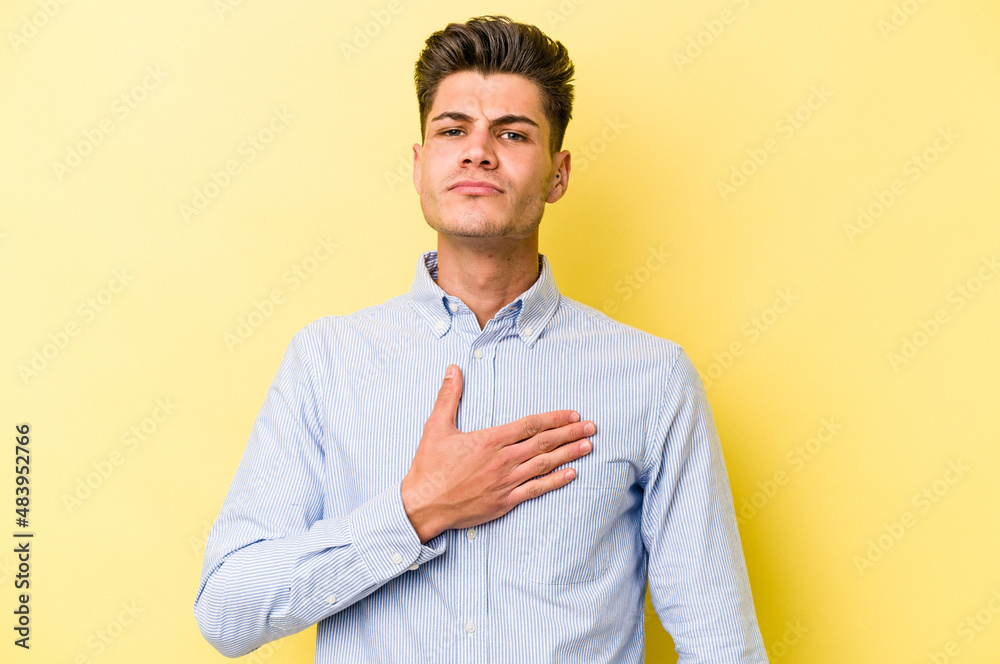 Young caucasian man isolated on yellow background taking an oath, putting hand on chest. Young caucasian man isolated on yellow background taking an oath, putting hand on chest.