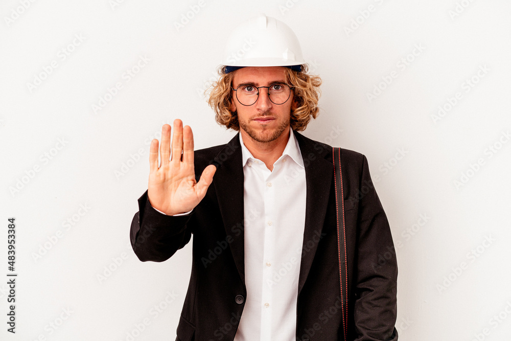 Young architect caucasian man with helmet isolated on white background standing with outstretched hand showing stop sign, preventing you. Young architect caucasian man with helmet isolated on white background standing with outstretched hand showing stop sign, preventing you.
