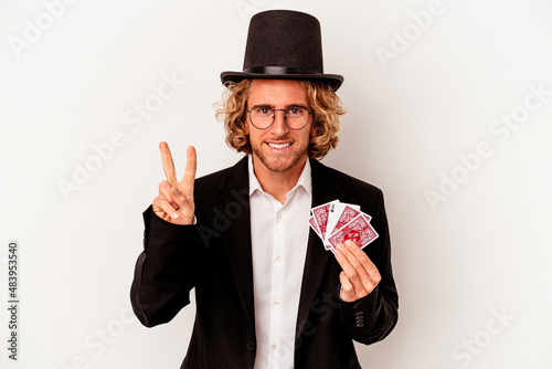 Young magician caucasian man holding magic cards isolated on white background showing number two with fingers.