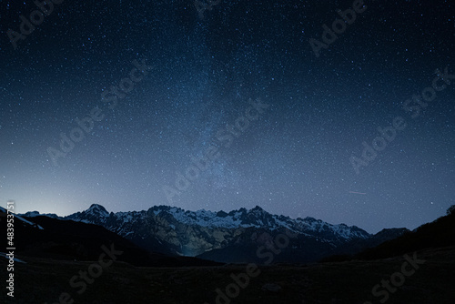 night sky full of stars over snow mountains in winter