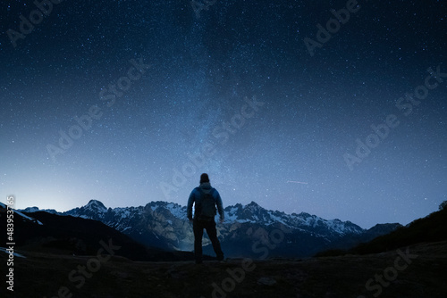 man standing under th night sky looking to the mountains