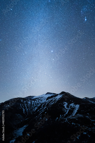 night sky full of stars over snow mountains in winter