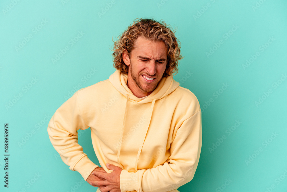 Young caucasian man isolated on blue background having a liver pain, stomach ache. Young caucasian man isolated on blue background having a liver pain, stomach ache.