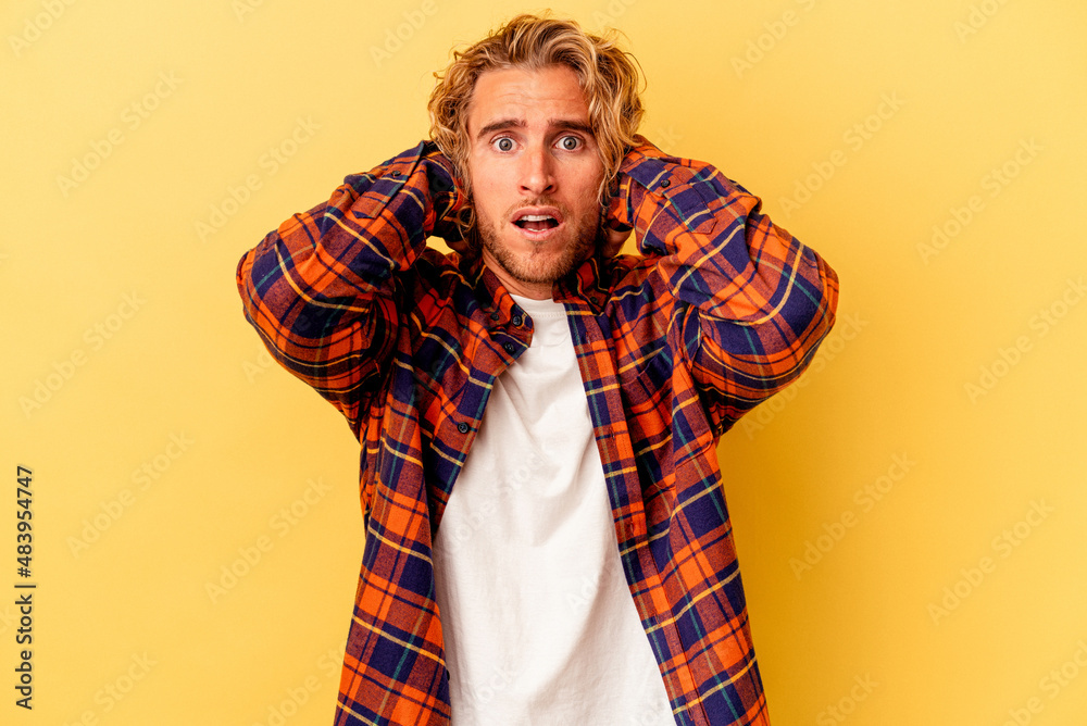 Young caucasian man isolated on yellow background screaming with rage. Young caucasian man isolated on yellow background screaming with rage.