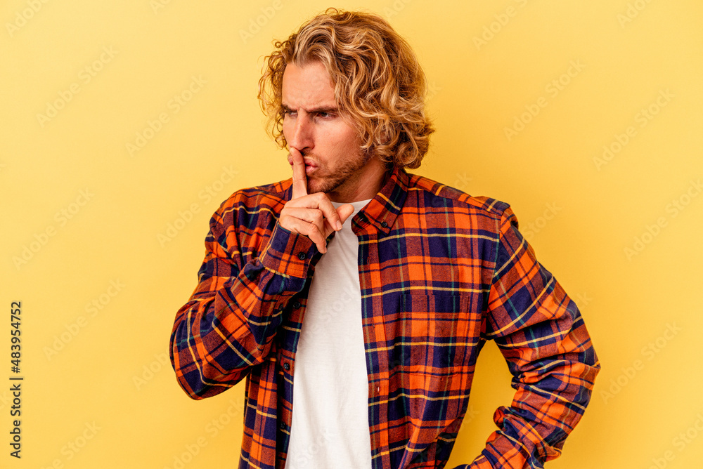 Young caucasian man isolated on yellow background keeping a secret or asking for silence.