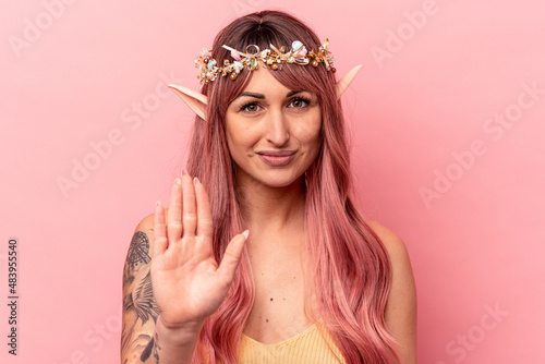 Young caucasian elf woman isolated on pink background standing with outstretched hand showing stop sign, preventing you. © Asier