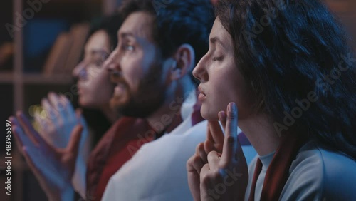 Close up view of the worried football fans watching game on TV, praying for victory and crossed fingers. Nervous woman at the first plan. Football fans at home concept.