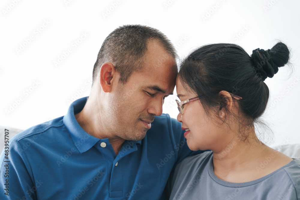 Portrait of Asian mature couple sitting in the living room. wife and husband hugging, holding hand with happiness and cheerful. Love, safety, and insurance family concept. Portrait of Asian mature couple sitting in the living room. wife and husband hugging, holding hand with happiness and cheerful. Love, safety, and insurance family concept.