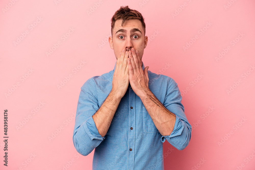 Young caucasian man isolated on pink background shocked covering mouth with hands. Young caucasian man isolated on pink background shocked covering mouth with hands.