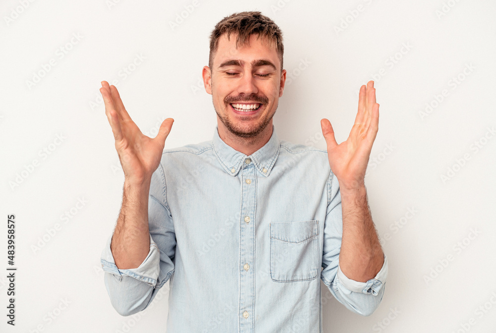 Fototapeta premium Young caucasian man isolated on white background smiling and showing a heart shape with hands.