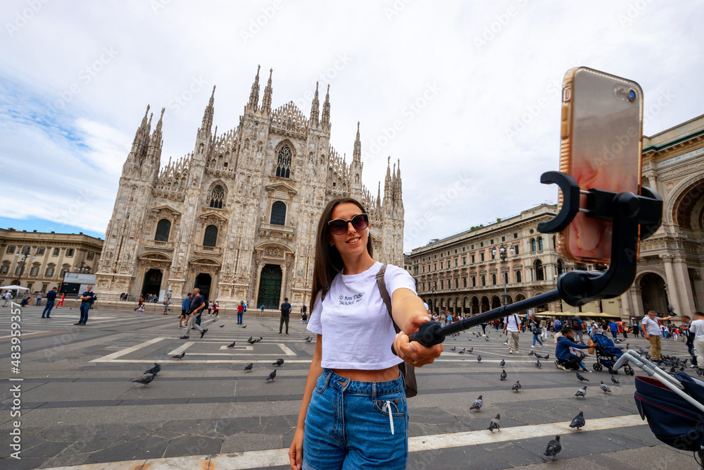 Influence media Milan Italy. Paint building house in Europe Milano city. Travel photographer blogger girl with smartphone in Piazza del Duomo. Freedom, summer travel, profession concept.
