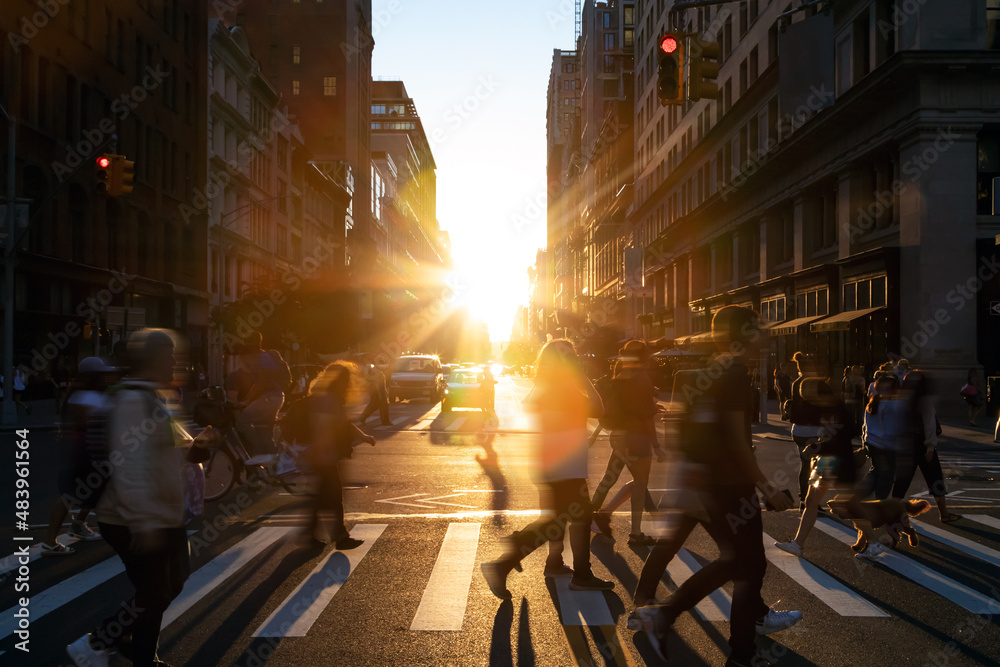 Diverse group of people walking across the crowded intersection at 23rd Street and 5th Avenue in New York City with light of sunshine in the background
