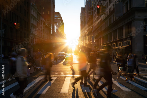 Diverse group of people walking across the crowded intersection at 23rd Street and 5th Avenue in New York City with light of sunshine in the background photo