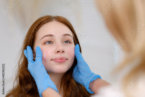 A young red-haired beautiful girl undergoes a medical examination in a cosmetology clinic. A female dermatologist consultation.