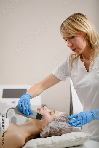 Ultrasonic procedure in a cosmetology clinic. A woman has course of machine hardware cosmetic procedures. Beautiful face close up.