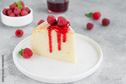 Japanese cotton cheesecake on a stand on a gray concrete background with fresh raspberries and powdered sugar on top. Selective focus  copy space.