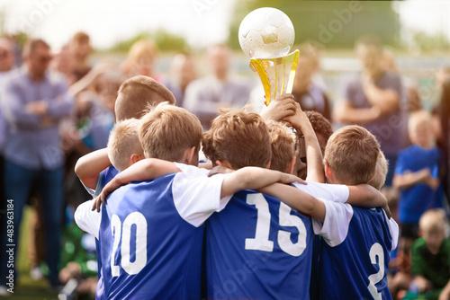 Happy Kids in a Team Rising Golden Trophy During Tournament Celetration. Summer Soccer Competition For Young Boys. Children in Blue Jersey Shirts in a Team Circle