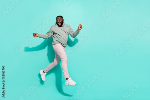Full length body size view of attractive cheerful guy jumping going enjoying isolated over bright teal turquoise color background