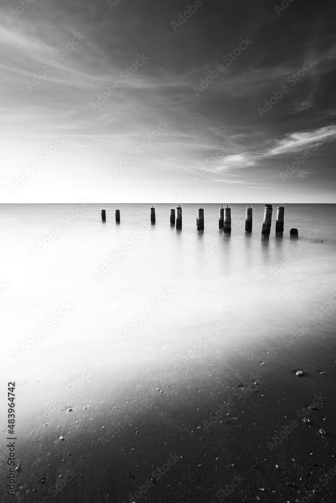 Black and White fine art images of a pillars in a beach with long exposure shot .