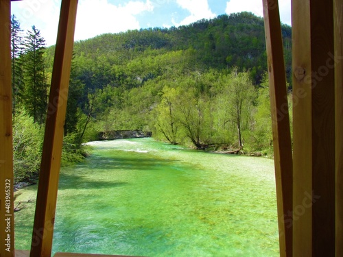 Sava Bohinjka river in Gorenjska, Slovenia and forest covered hill behind photo