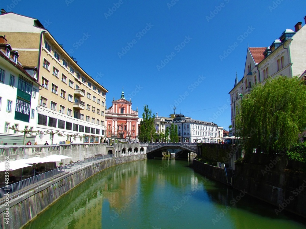 Ljubljanica river flowing through Ljubljana city in Slovenia and the Franciscan Church of the Annunciation and a reflection of the buildings in the river