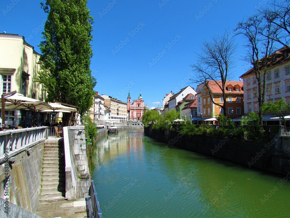 Obraz premium Ljubljanica river flowing through Ljubljana city in Slovenia and the Franciscan Church of the Annunciation and a reflection of the buildings in the river