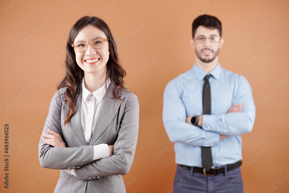 Happy smiling confident female team leader standing with arms crossed in front of her colleague and looking at camera Happy smiling confident female team leader standing with arms crossed in front of her colleague and looking at camera