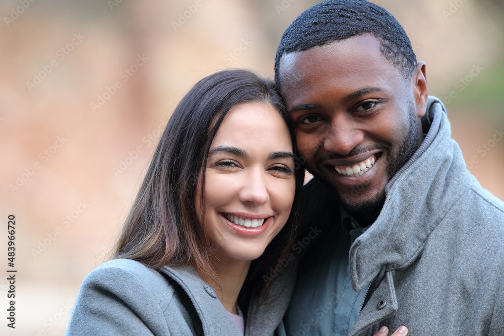 Happy interracial couple looking at camera in winter Happy interracial couple looking at camera in winter