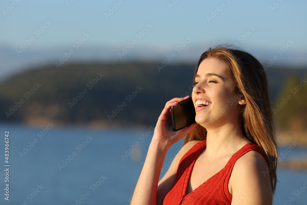 Happy woman in red talking on phone in nature