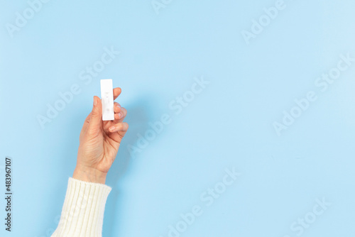 Female hand holding rapid Coronavirus Covid-19 test device with negative test result on light blue background photo