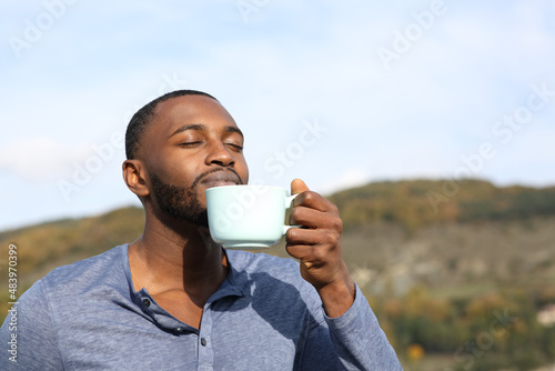 Man with black skin drinking and smelling coffee