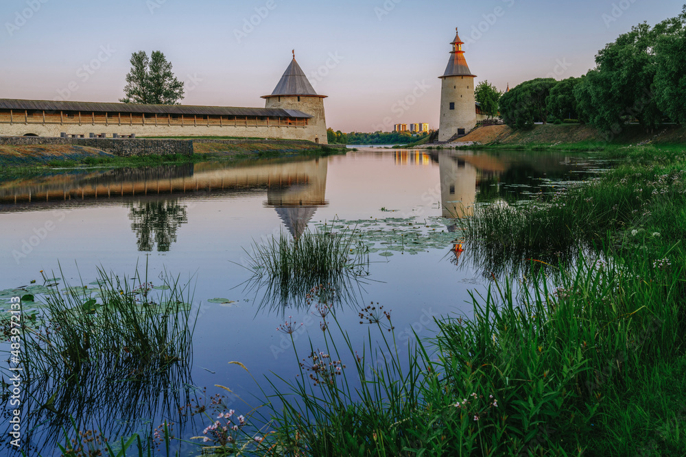View of the Pskov Kremlin wall, High (Vysokaya) and Flat (Ploskaya) towers on the bank of the Pskova River on an early summer morning, Pskov, Russia