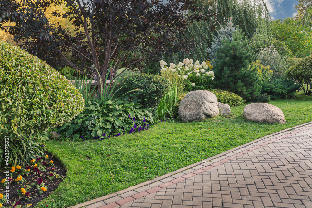 Fototapeta premium Paved alley of the park with trimmed bushes and trees. Topiary art. Landscaping.