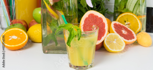 against the background of sliced fresh citrus fruits, a glass of freshly squeezed oranges and a glass jug with lemonade