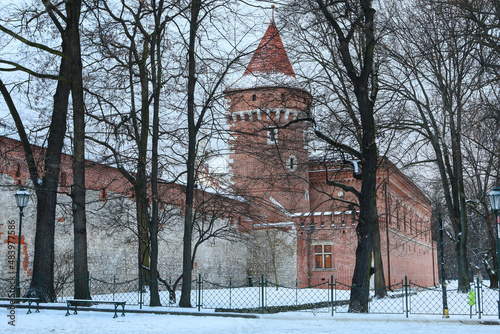 KRAKOW, POLAND - JANUARY 21, 2022: A brick tower and alleys covered with snow in Krakow, Poland.